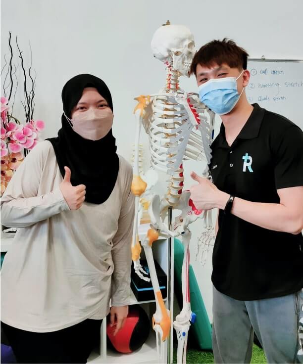 Jaffery and his patient are giving thumbs up next to a human skeleton model in a clinic